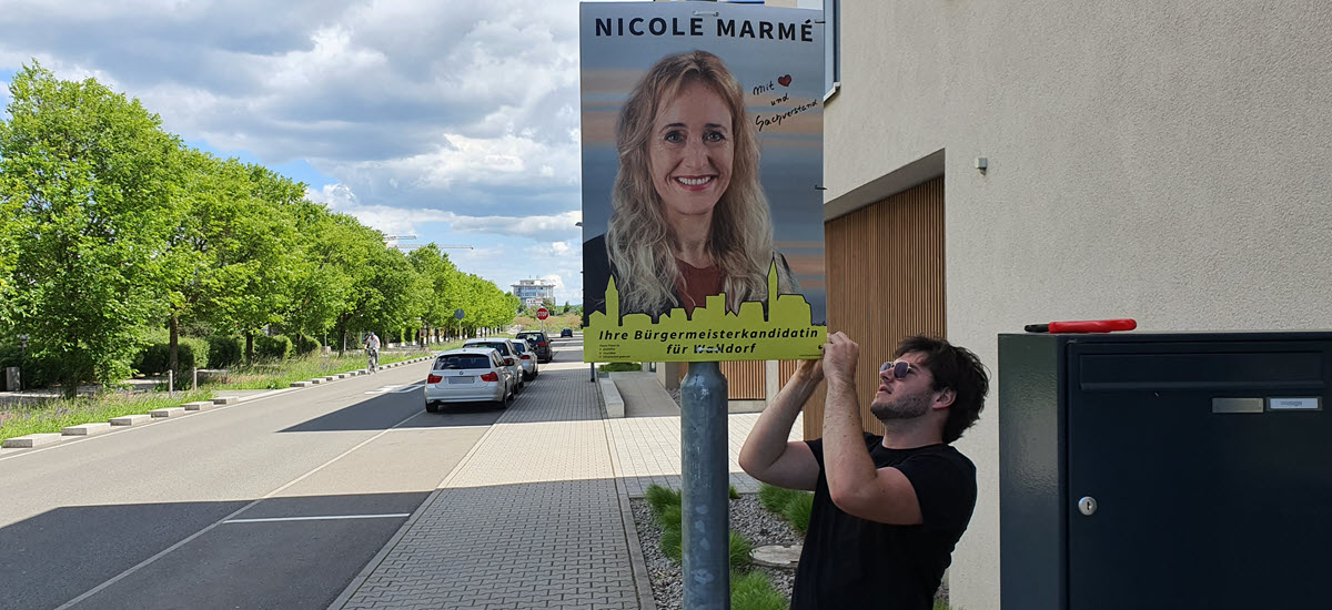 Max Hartl hängt in der Bürgermeister Willinger Str. ein Plakat von Nicole Marmé auf | Foto: Dr. Clemens Kriesel
